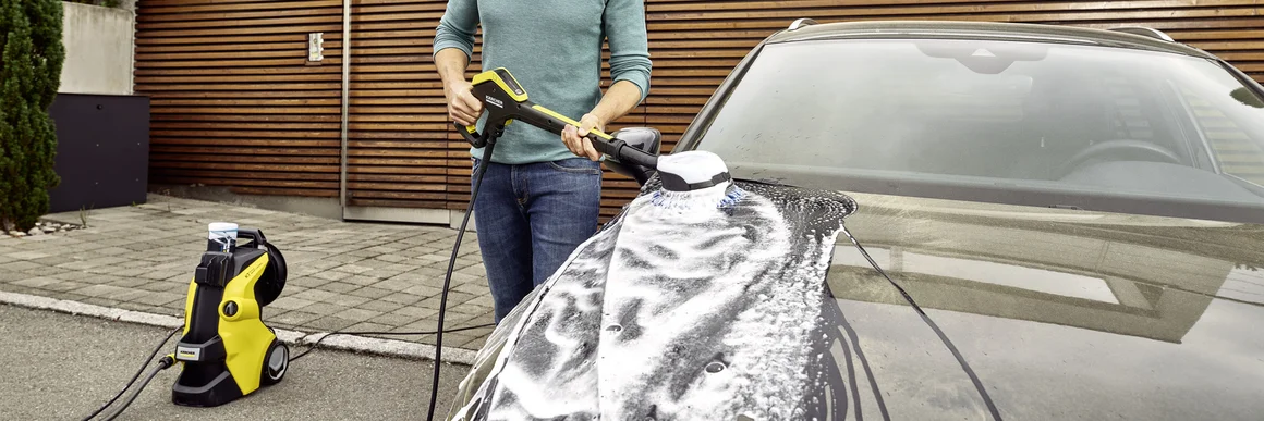 Person wäscht Auto mit Hochdruckreiniger